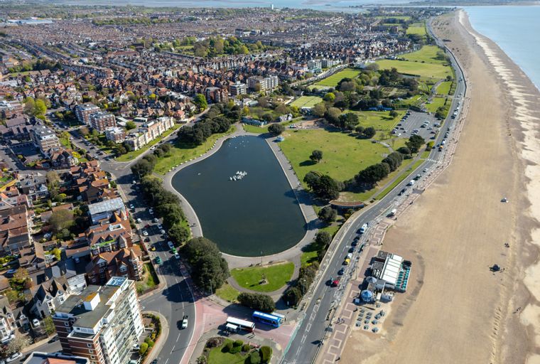 An aerial view of a coastal town with a lake, park, and beach.