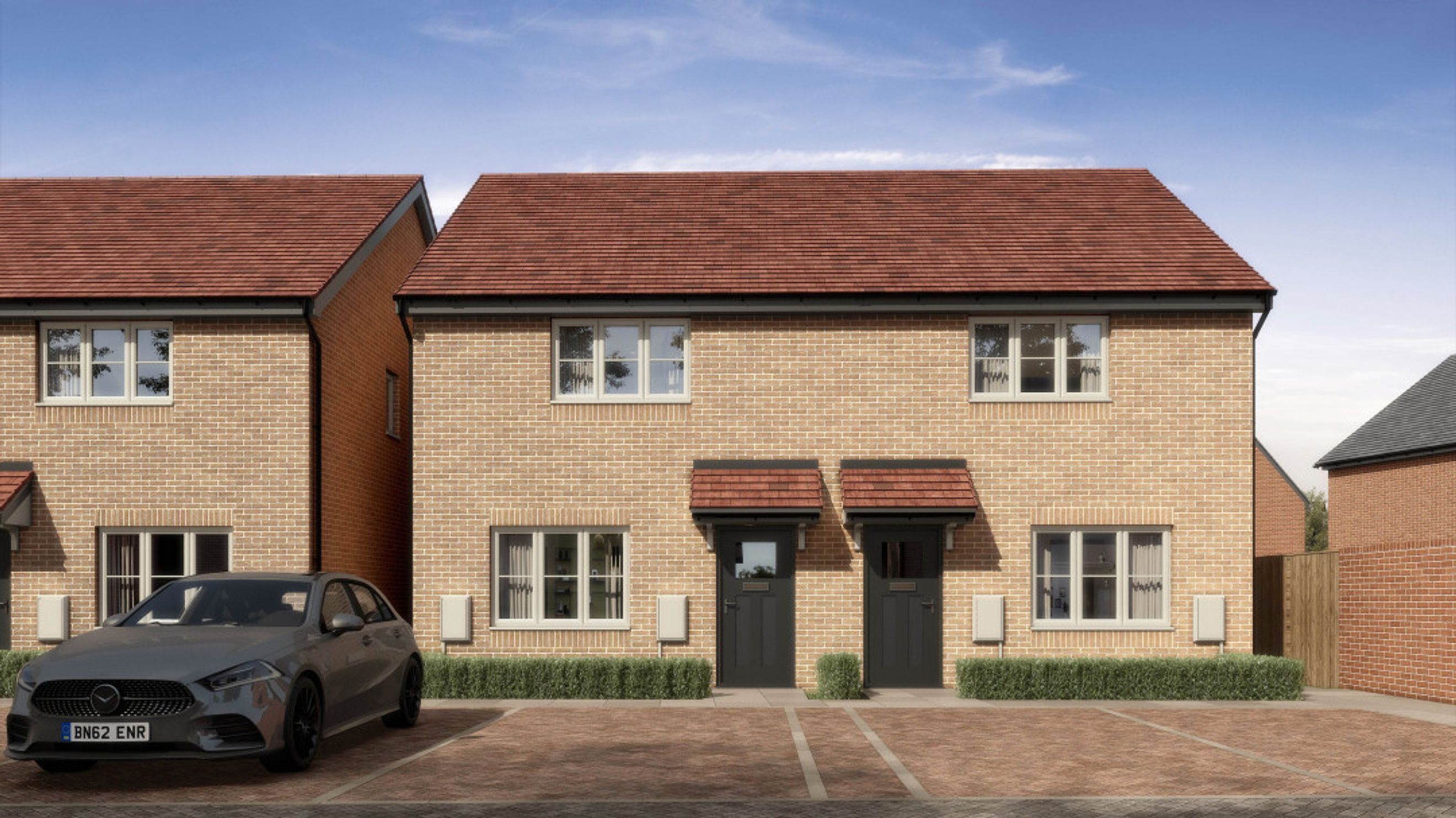 A pair of semi-detached houses with a car parked in the driveway.