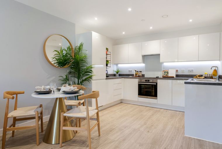A dining area and kitchen with white cabinets, a marble table, and wooden chairs.