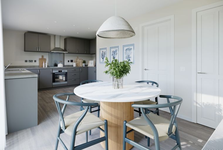 A dining area with a round table and chairs next to a kitchen.