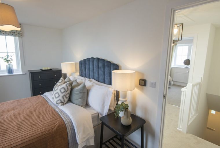 A bedroom with a bed, bedside tables, lamps, and a dresser.