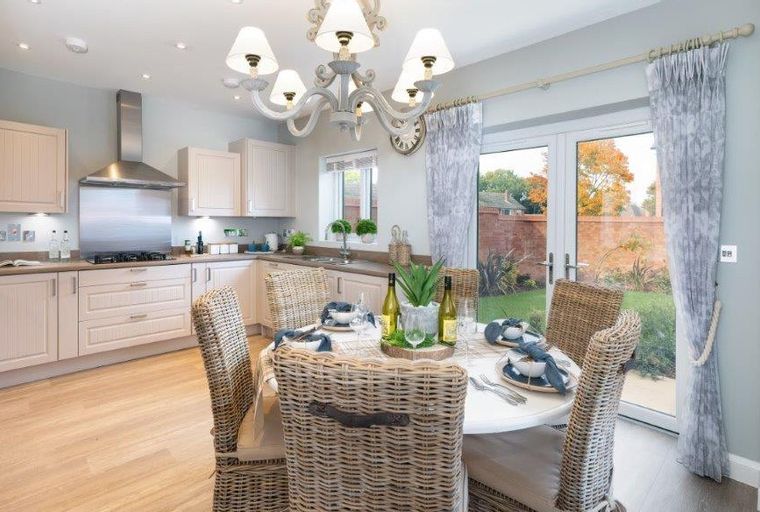A kitchen and dining area with a table set for a meal and a view of a garden through glass doors.