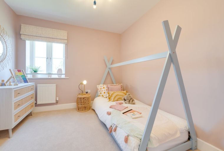 A children's bedroom with a teepee bed, dresser, and mirror.