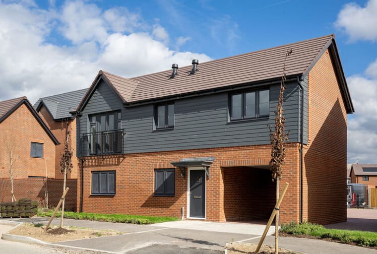 A modern brick house with grey cladding and dark windows.