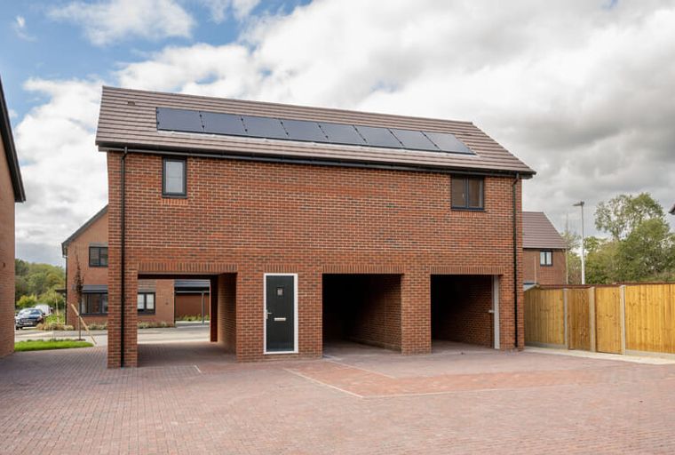 A modern brick house with solar panels on the roof and an open-plan garage.