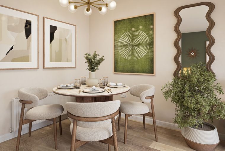 A dining area with a round table, chairs, and artwork on the wall.