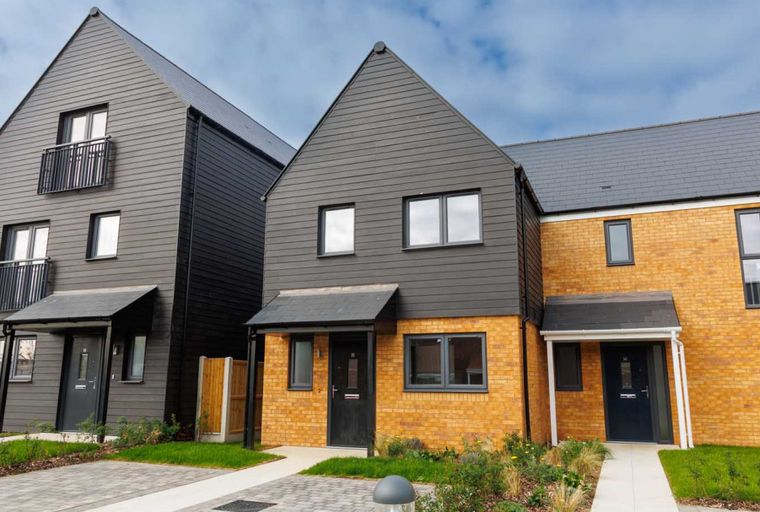 A row of modern houses with dark grey siding and yellow brick exteriors.