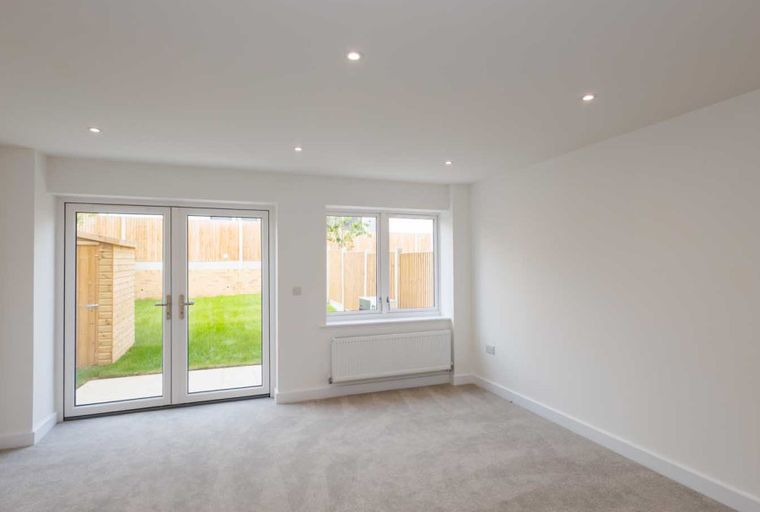 A living room with double doors, a window, and a radiator.
