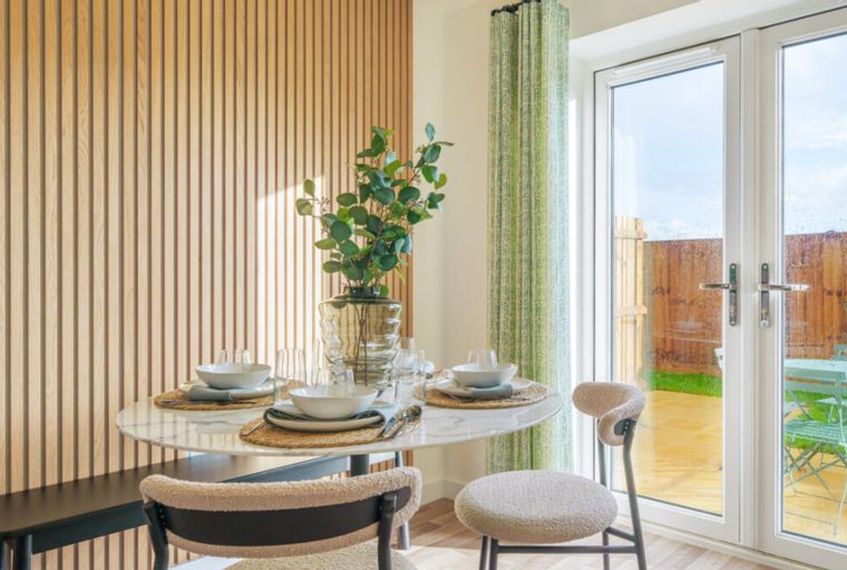 A dining area with a marble table, chairs, and a wooden slat wall.