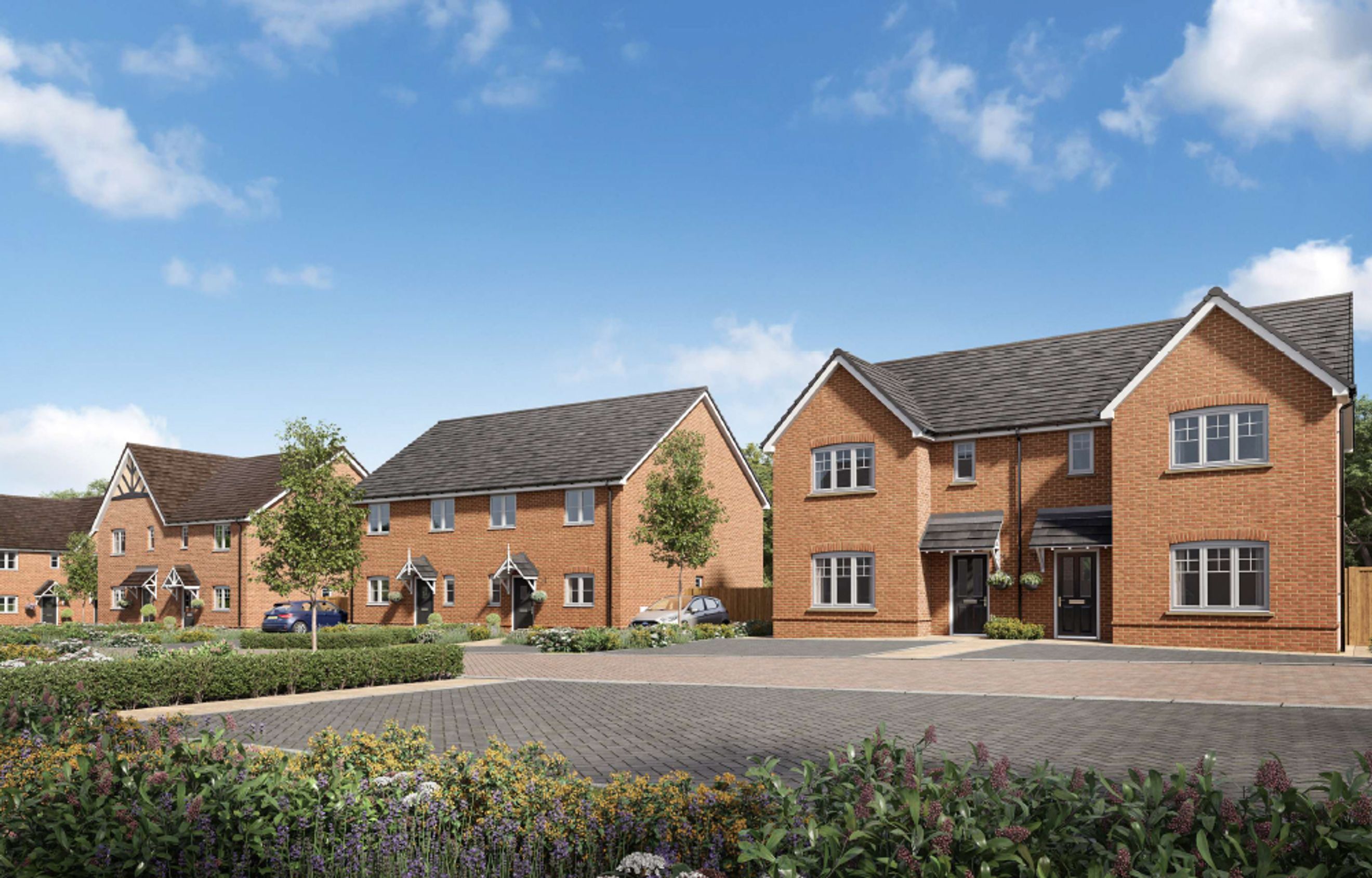 A row of modern brick houses with grey tiled roofs and manicured gardens under a blue sky.