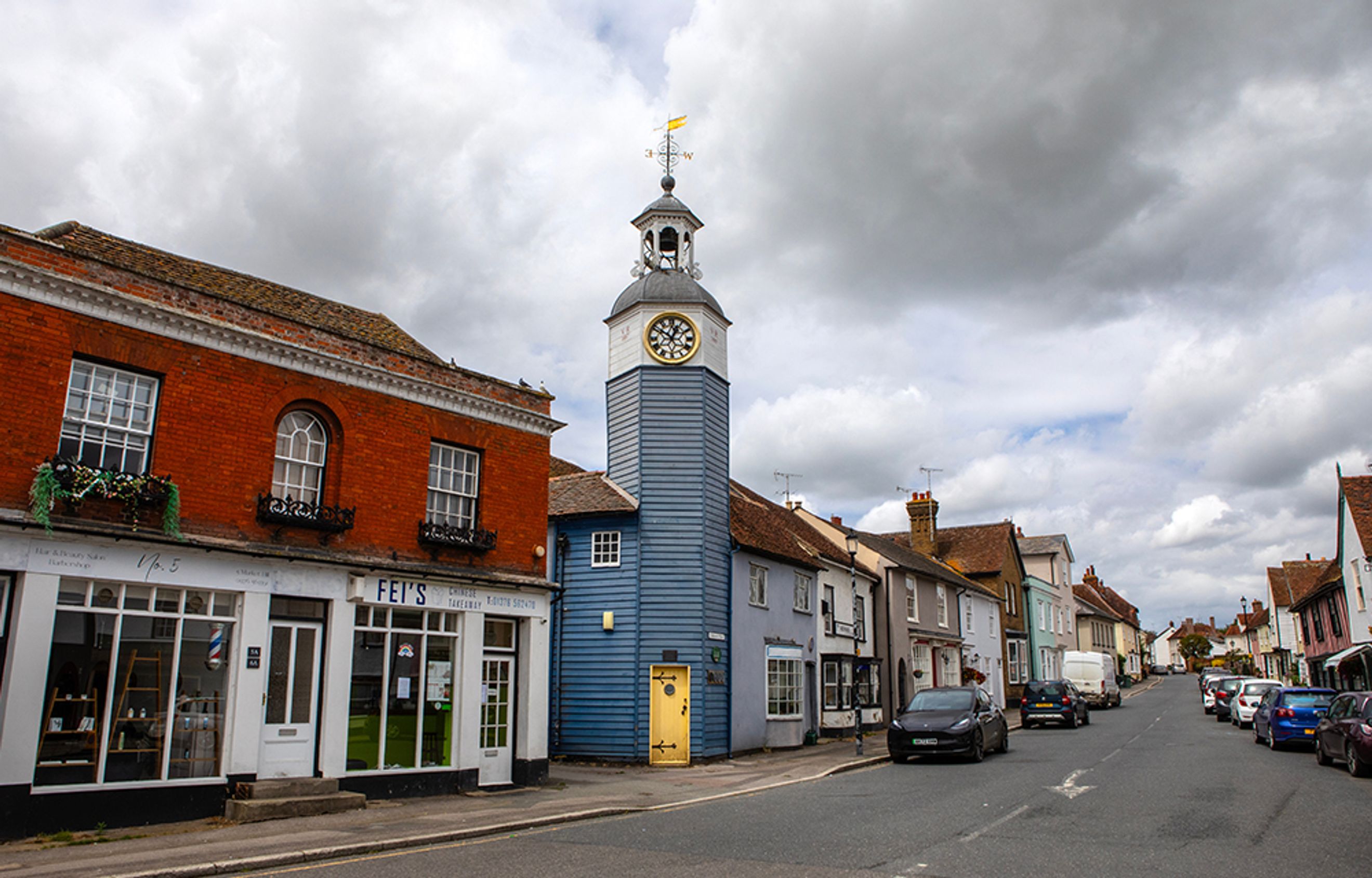 A street view of a town with a clock tower and shops.