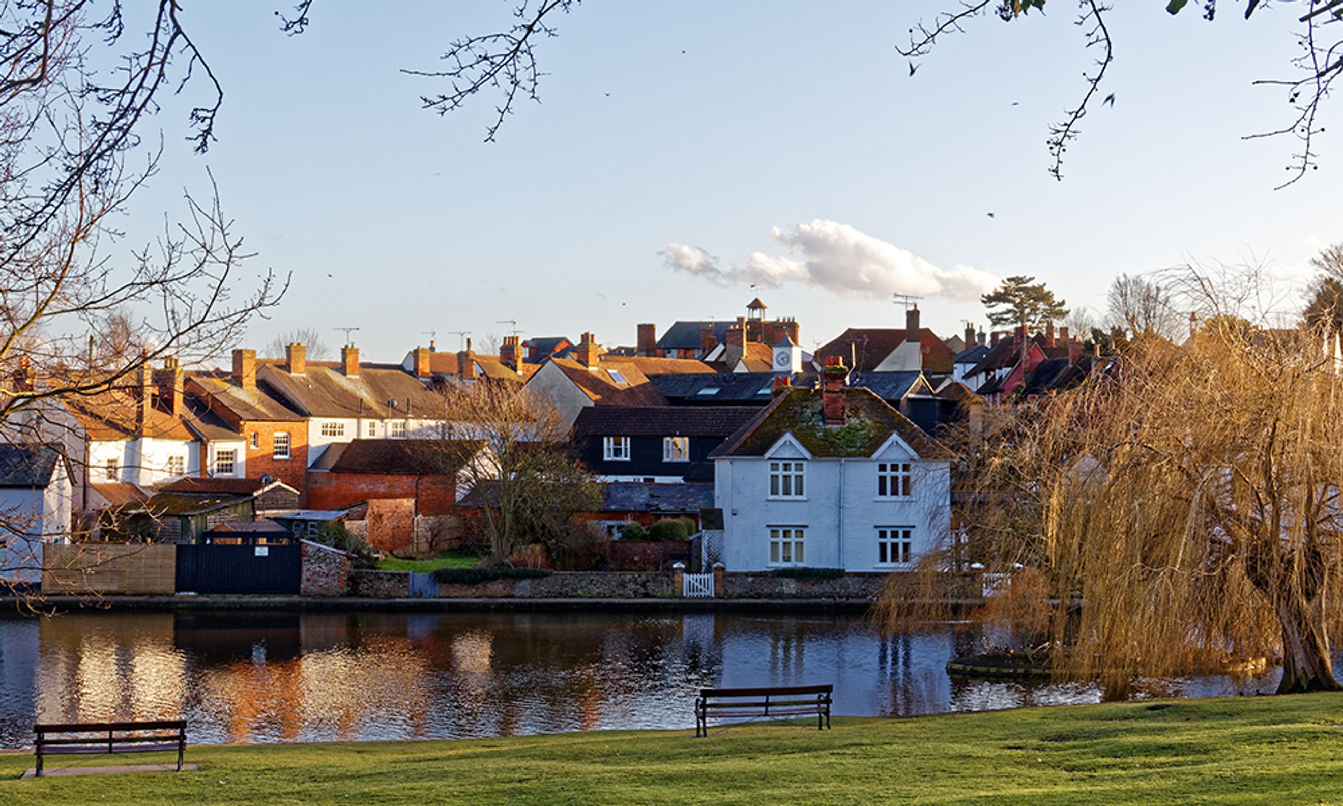A waterfront view of houses with a river in the foreground and trees.