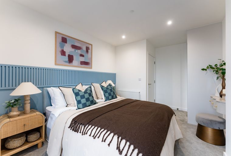 A bedroom with a bed, nightstand, and artwork.
