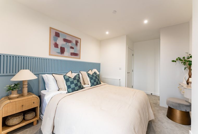 A bedroom with a bed, headboard, and bedside table.