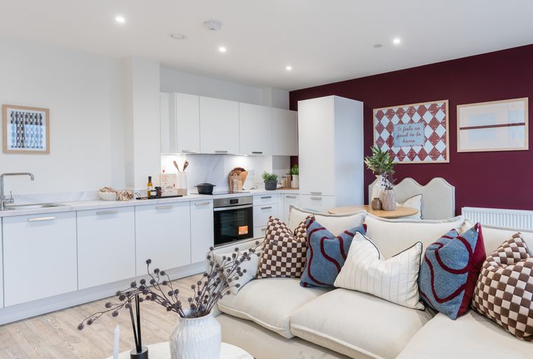 A living room and kitchen area with a sofa, dining table, and white cabinets.