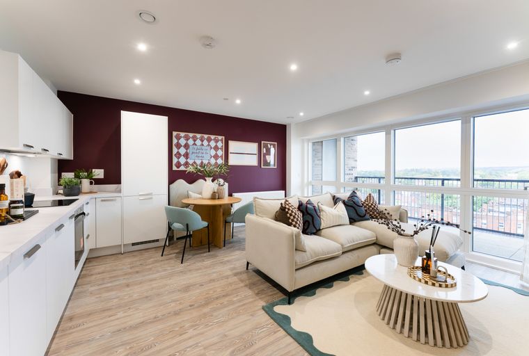 A modern living room and kitchen area with a sofa, dining table, and kitchen cabinets.