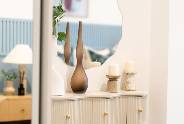A vanity table with a mirror, stool, and decorative items.