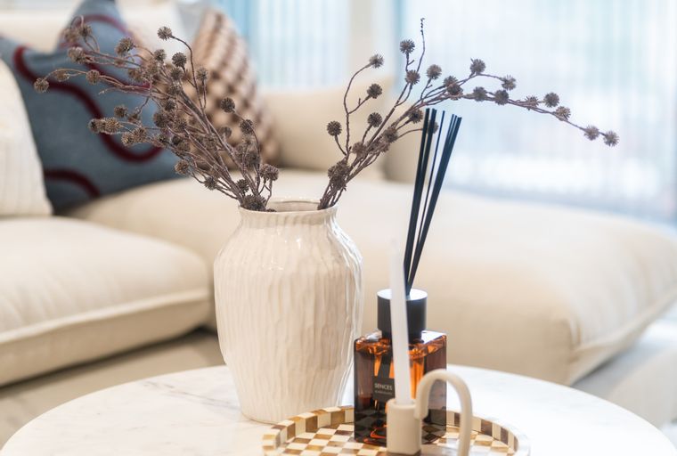 A marble coffee table with decorative items including a vase, diffuser, and candle holder.