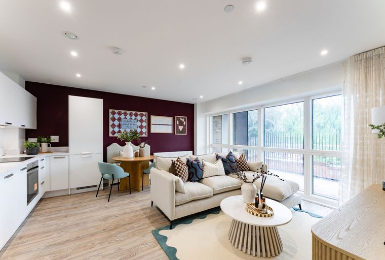 A living room and kitchen area with a sofa, coffee table, dining table, and kitchen cabinets.