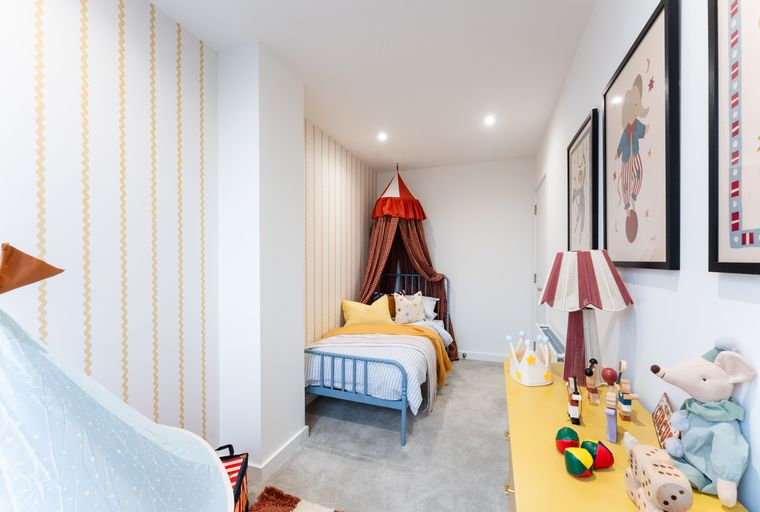 A children's bedroom with a bed, dresser, and circus-themed decor.