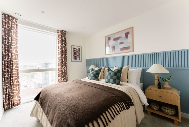 A bedroom with a bed, pillows, a throw blanket, and a nightstand.