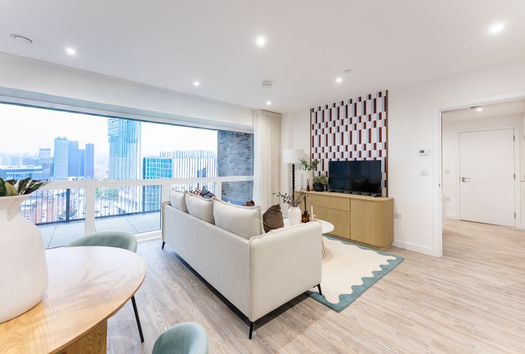 A living room with a sofa, TV, and a large window overlooking a city skyline.